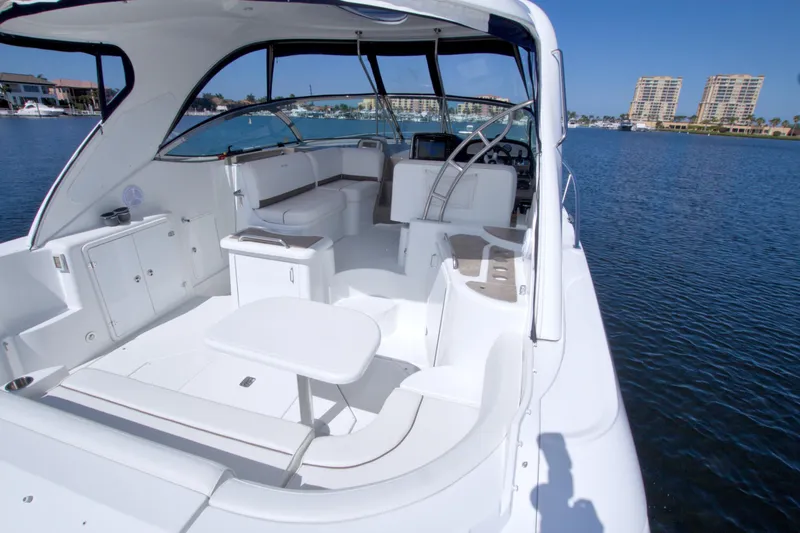 Slide: The Image of 2008 Cruisers Yachts 420 Express interior with seating, table, and helm, docked on calm water. - 22