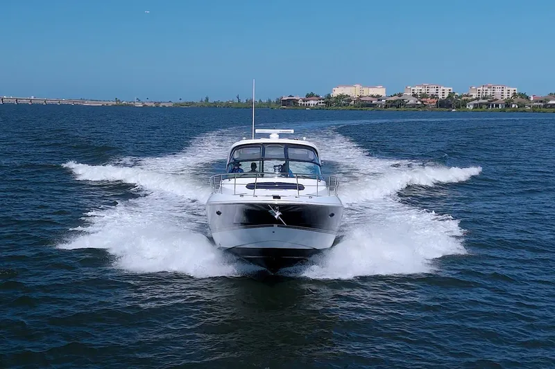 Slide: The Image of 2008 Cruisers Yachts 420 Express speeding on open water near coastal cityscape. - 5