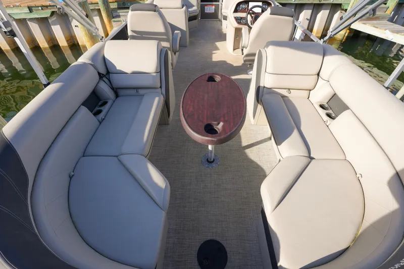 Slide: The Image of 2023 Berkshire 24 RFX LE 2.75 pontoon boat interior with beige seating and wooden table. - 10