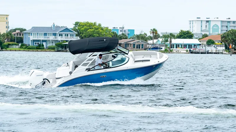 Slide: The Image of 2026 Sea Ray SDX 230 Outboard cruising on water near coastal homes. - 0