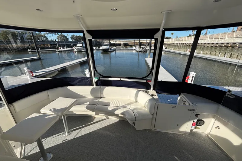 Slide: The Image of 2005 Cruisers Yachts 455 Express Motoryacht aft deck area with marina view, featuring seating, tables and Strataglass Enclosure. - 7