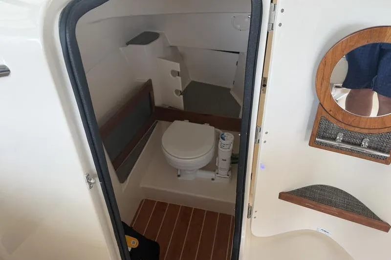 Slide: The Image of Interior of 2026 Grady-White Freedom 285 boat, featuring a compact marine toilet. - 16