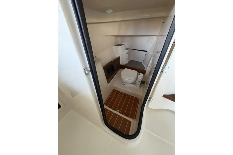 Slide: The Image of 2026 Grady-White Freedom 285 boat interior with compact bathroom and wooden flooring. - 29