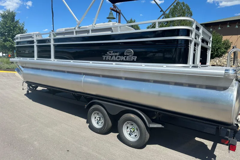 Slide: The Image of 2026 Sun Tracker SportFish 22 DLX pontoon boat on trailer, parked outdoors. - 103
