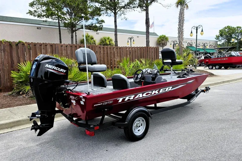 Slide: The Image of 2026 Tracker Pro 170 boat with Mercury engine, parked outdoors near greenery. - 2