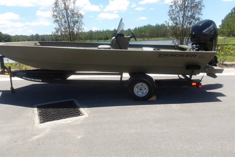 The Image of 2026 Tracker Grizzly 2072 CC boat on trailer, parked near a scenic lake. - 1