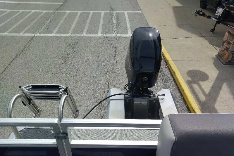 Slide: The Image of 2026 Sun Tracker Bass Buggy 16 XL Select pontoon boat with outboard motor in parking lot. - 81