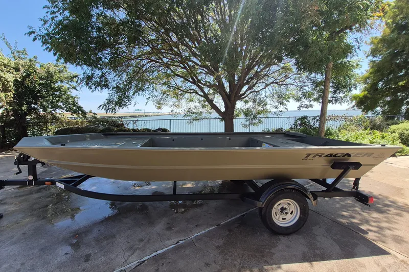 The Image of 2026 Tracker Grizzly 1754 Utility boat on trailer, parked near a scenic lakeside. - 0