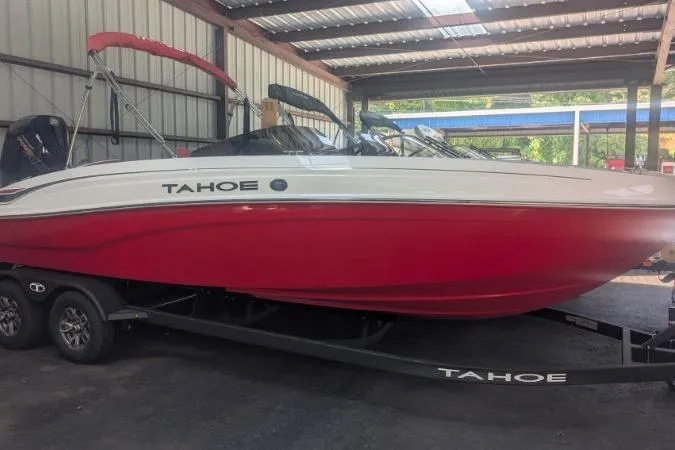 The Image of 2026 Tahoe T21 boat with red hull on trailer in covered storage. - 0
