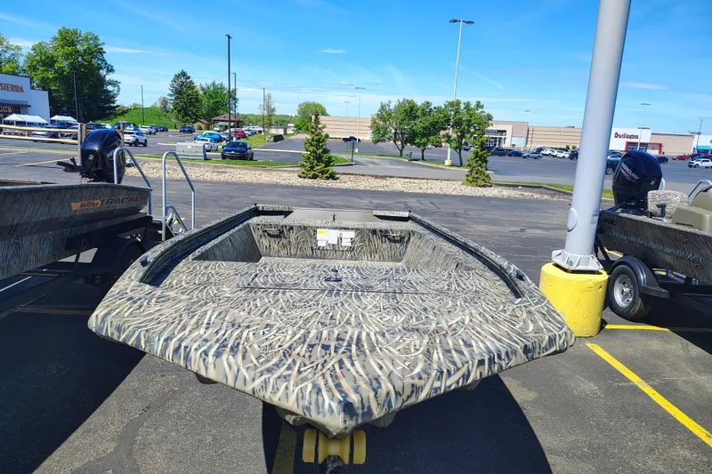 Slide: The Image of 2026 Tracker Grizzly 1648 Utility boat with camouflage design in a parking lot. - 2