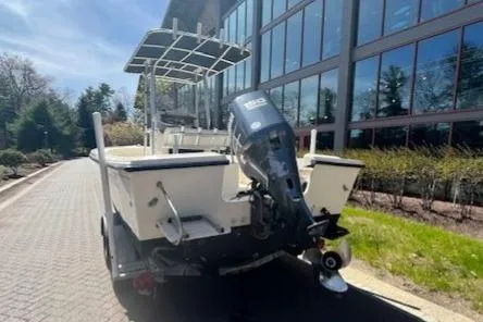 Slide: The Image of 2005 Parker 2100 Center Console boat with outboard motor, parked near a modern building. - 10