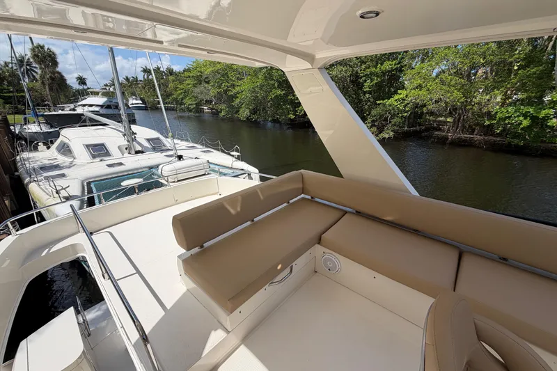 Slide: The Image of 2015 Carver 40 Command Bridge yacht with spacious deck and seating, docked by a scenic waterway. - 38