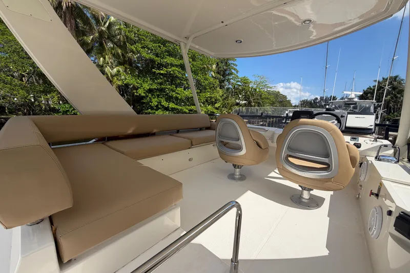 Slide: The Image of 2015 Carver 40 Command Bridge interior with beige seating and helm chairs, surrounded by lush greenery. - 40
