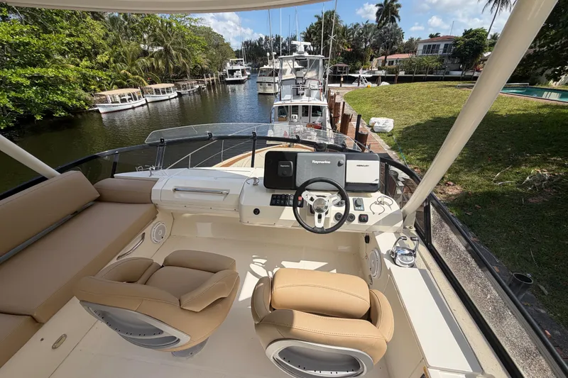 Slide: The Image of 2015 Carver 40 Command Bridge yacht interior with helm, luxurious seating, and scenic waterway view. - 48