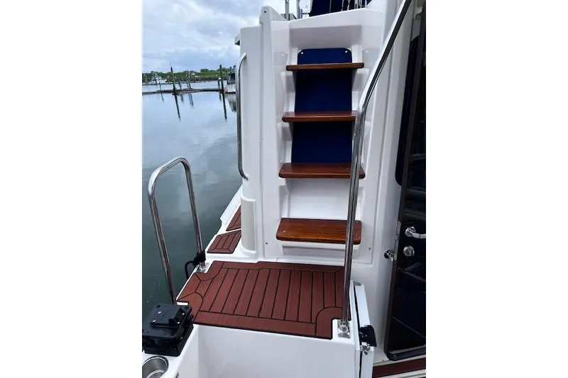 Slide: The Image of 2021 Ranger Tugs R-31 CB boat with wooden steps and railing by the water. - 33