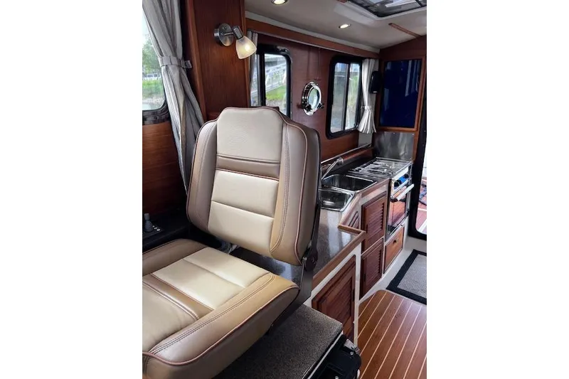 Slide: The Image of Interior of 2021 Ranger Tugs R-31 CB, featuring seating and compact kitchen area. - 44