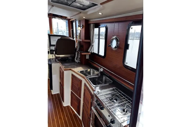 Slide: The Image of Interior of 2021 Ranger Tugs R-31 CB, featuring a compact kitchen with wood accents. - 46