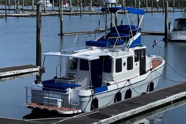 Slide: The Image of 2021 Ranger Tugs R-31 CB docked in a marina, featuring blue accents and spacious deck. - 7