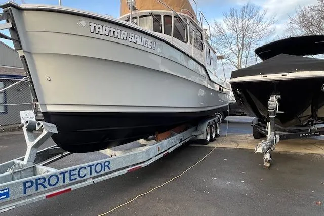 Slide: The Image of 2021 Ranger Tugs R-31 CB boat on trailer, labeled "Tartar Sauce," parked outdoors. - 79