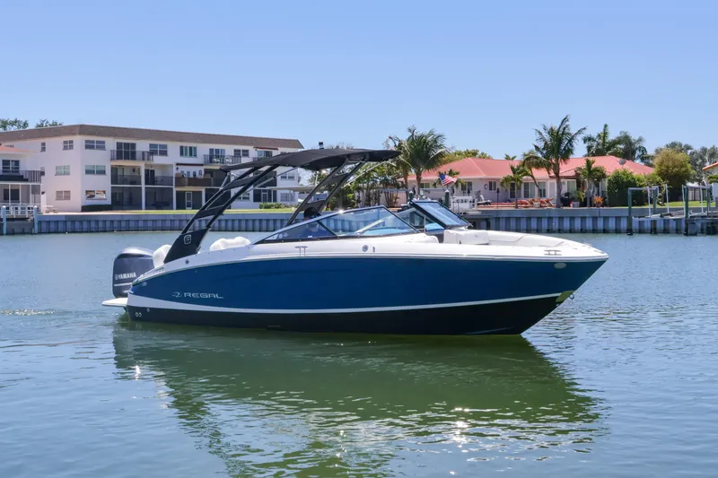 Slide: The Image of 2020 Regal LX4 boat on calm water near waterfront homes. - 2
