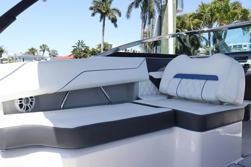 Slide: The Image of 2020 Regal LX4 boat interior with white and blue seating, palm trees in background. - 20