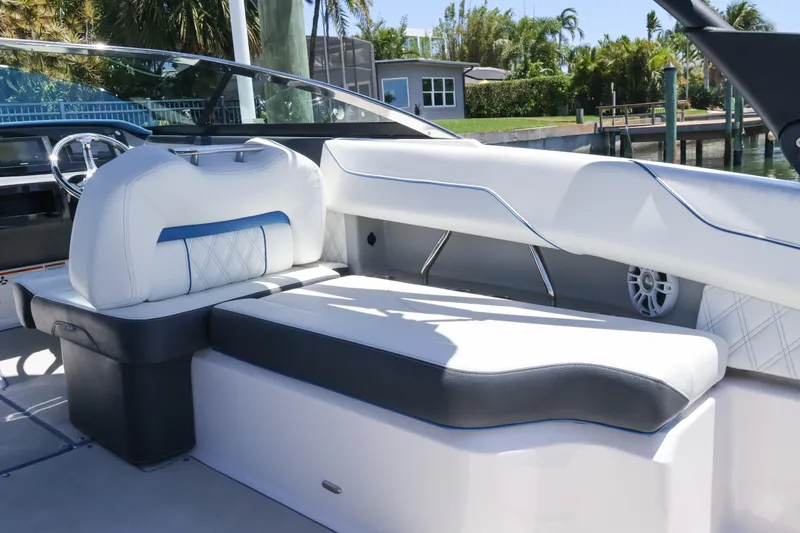 Slide: The Image of 2020 Regal LX4 boat interior with white and blue seating, docked near lush greenery. - 21