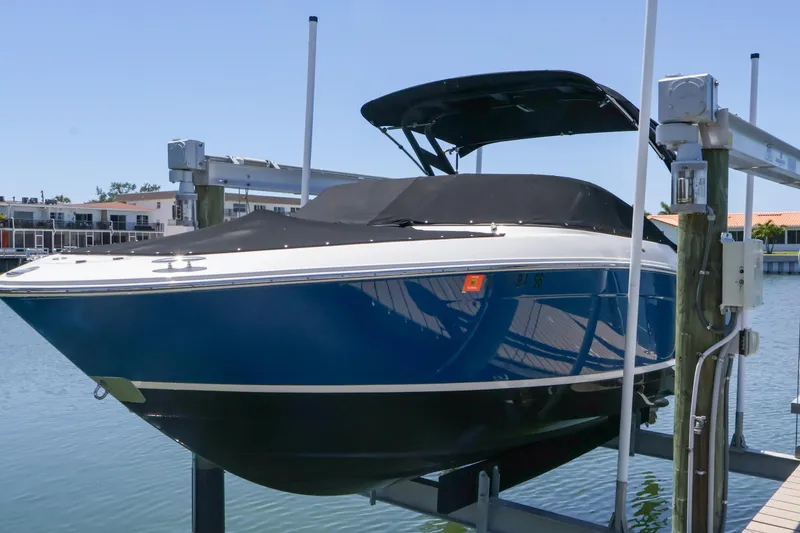 Slide: The Image of 2020 Regal LX4 boat on lift, blue hull, covered, dockside view. - 6