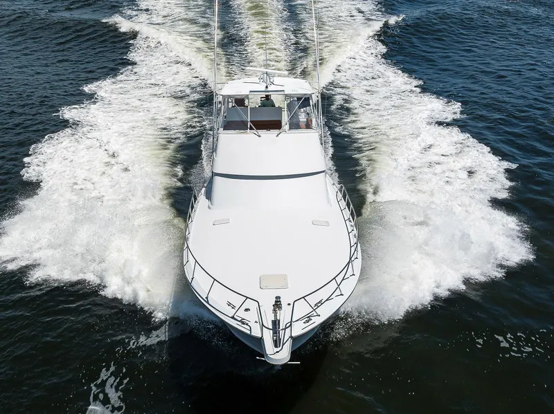 Slide: The Image of 2001 Hatteras 60 Convertible yacht cruising on open water, creating a dynamic wake. - 2