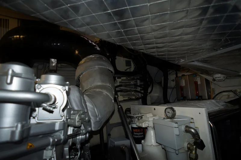 Slide: The Image of Engine room of a 2016 Pershing 70 yacht, showcasing mechanical components and piping. - 45