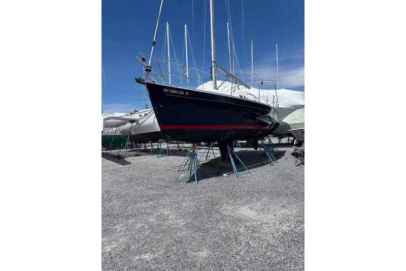 The Image of 1995 Beneteau Oceanis 321 sailboat on stands in a gravel boatyard. - 0