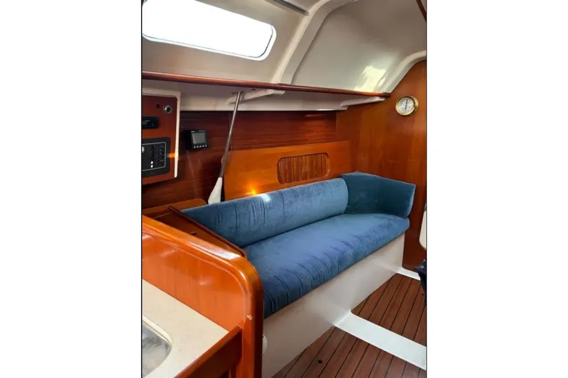 Slide: The Image of Interior of 1995 Beneteau Oceanis 321 sailboat with blue cushioned seating and wooden paneling. - 10