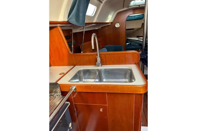 Slide: The Image of Interior of 1995 Beneteau Oceanis 321 sailboat featuring a compact wooden galley with sink. - 13