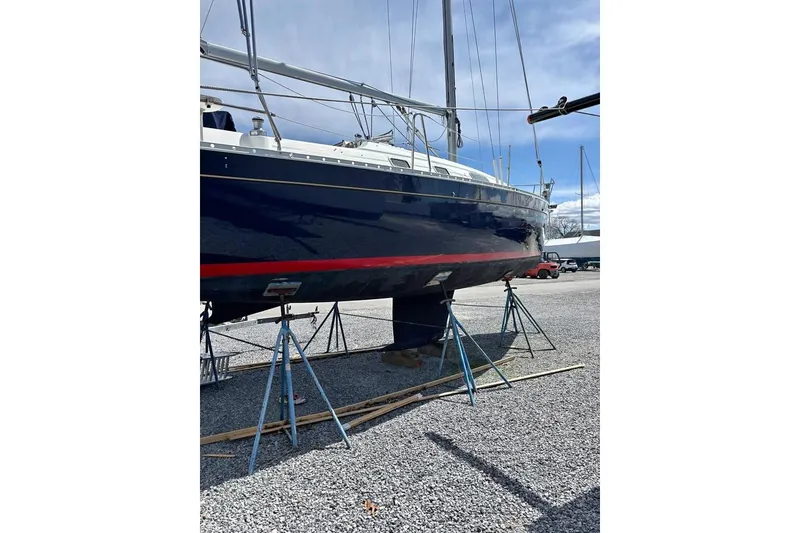 Slide: The Image of 1995 Beneteau Oceanis 321 sailboat on stands, blue hull with red stripe. - 2