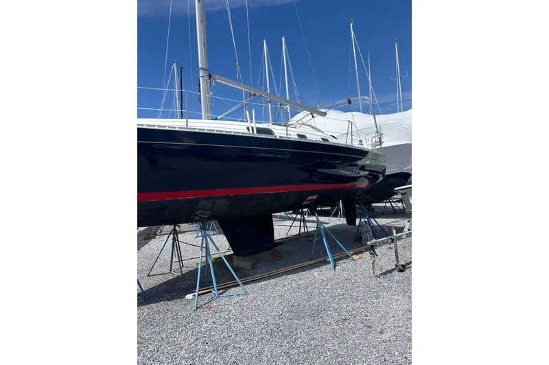 Slide: The Image of 1995 Beneteau Oceanis 321 sailboat on stands, blue hull, red stripe, marina setting. - 4