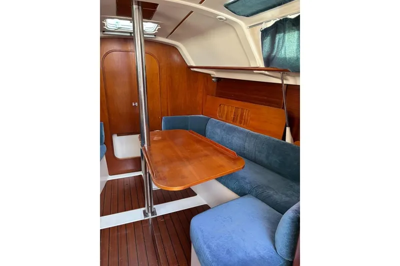 Slide: The Image of Interior of 1995 Beneteau Oceanis 321 sailboat with wooden table and blue seating. - 9