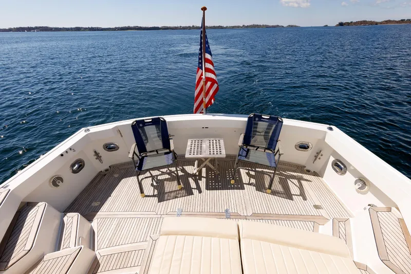 Slide: The Image of Luxury Eastbay 49 yacht deck with chairs, table, and American flag, cruising on open water. - 13