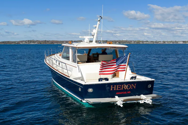 Slide: The Image of Eastbay 49 yacht from 2000 on open water, displaying American flag, named "Heron." - 2