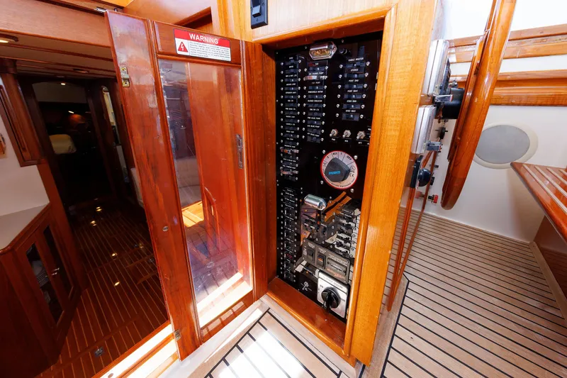 Slide: The Image of Electrical panel inside a 2000 Eastbay 49 yacht, featuring wooden cabinetry and detailed controls. - 26
