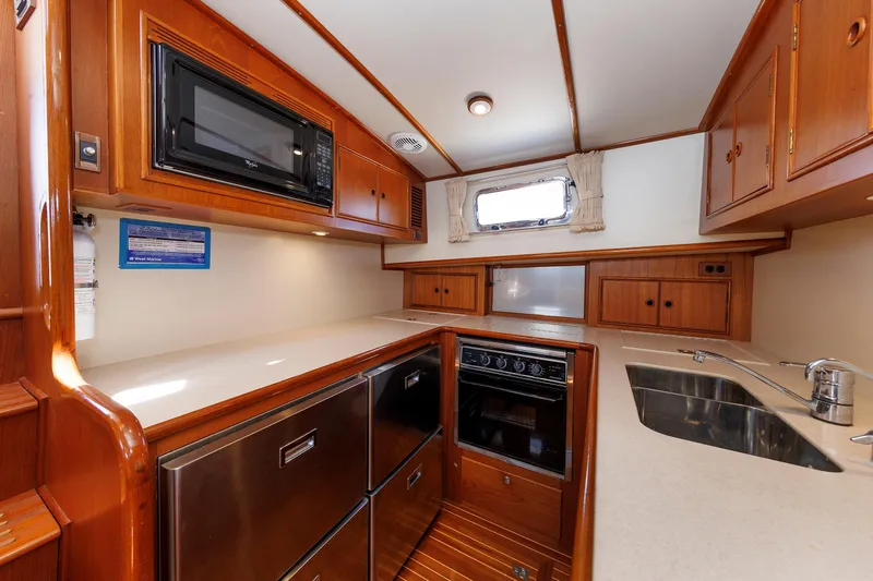 Slide: The Image of Luxurious Eastbay 49 yacht kitchen with wood cabinetry, microwave, stove, and sink, year 2000 model. - 30