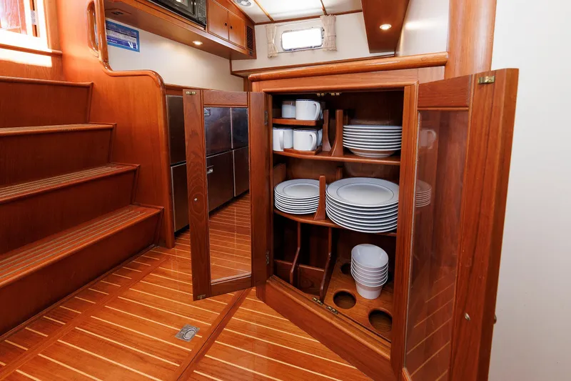 Slide: The Image of Wooden yacht interior with open cabinet displaying neatly arranged dishes and cups. - 32