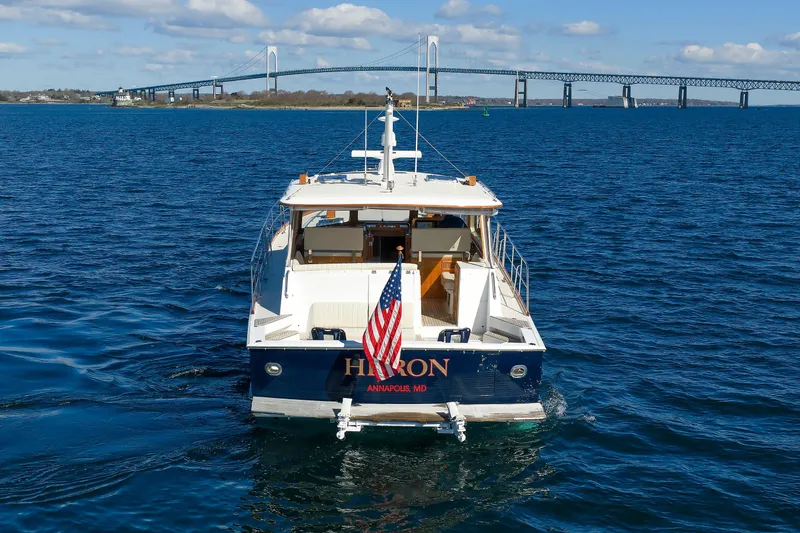 Slide: The Image of Eastbay 49 yacht on water, American flag, bridge in background, clear sky. - 7