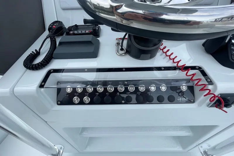 Slide: The Image of Control panel of a 2025 Hell's Bay Estero boat with switches and steering wheel. - 10