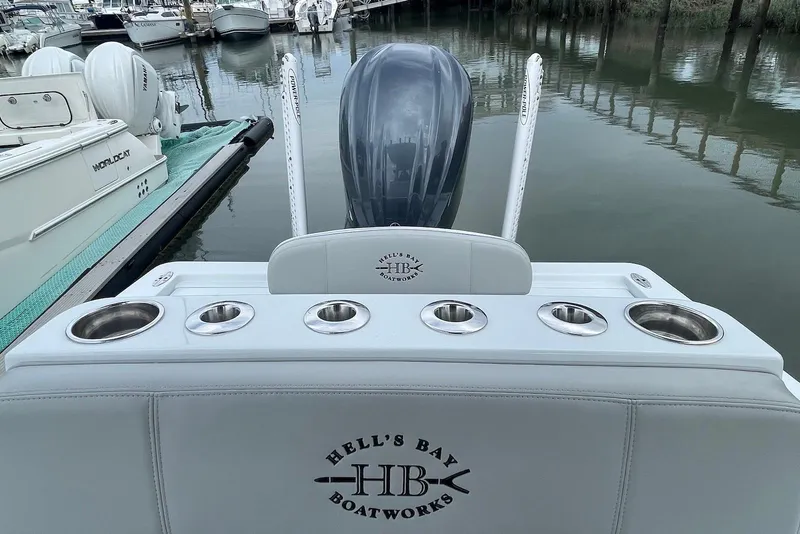 Slide: The Image of 2025 Hell's Bay Estero boat with motor, docked at marina, featuring cup holders. - 12