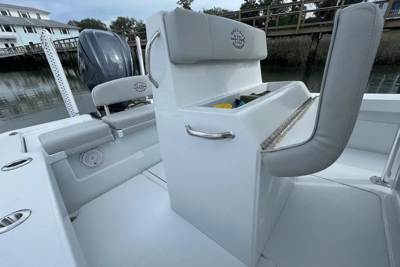 Slide: The Image of 2025 Hell's Bay Estero boat interior with seating and storage, docked by a wooden pier. - 18