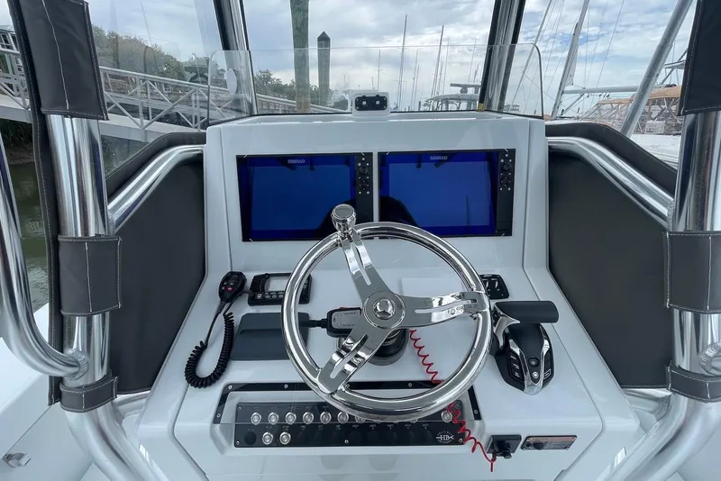 Slide: The Image of 2025 Hell's Bay Estero boat dashboard with dual screens and steering wheel. - 8
