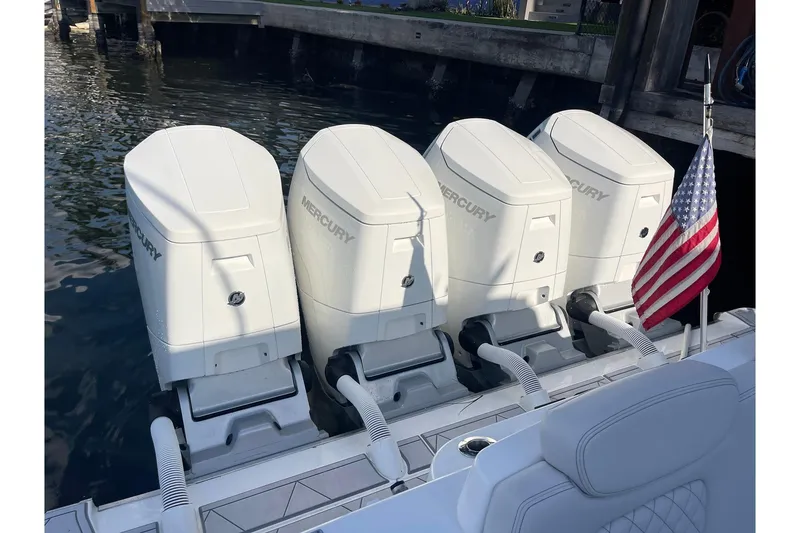 Slide: The Image of Four Mercury outboard engines on a 2024 HCB 48 Campeon boat, docked with an American flag. - 26