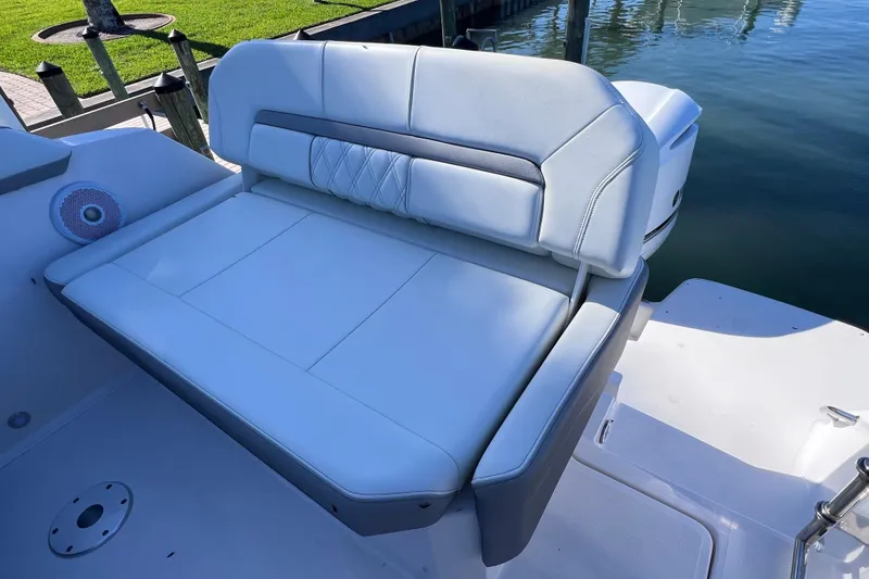 Slide: The Image of 2020 Regal 26 XO boat with cushioned seating by the water. - 15