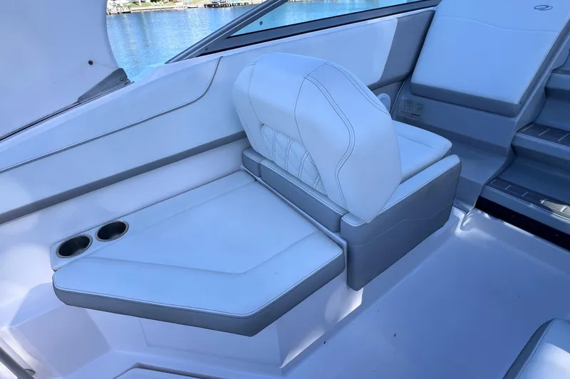 Slide: The Image of 2020 Regal 26 XO boat interior with white seating and cup holders by the water. - 20