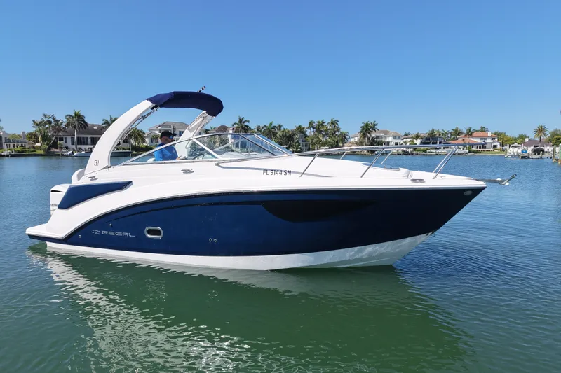 Slide: The Image of 2020 Regal 26 XO boat on calm water, with a scenic waterfront background. - 4