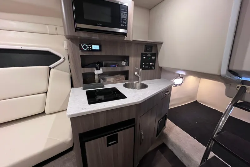 Slide: The Image of 2020 Regal 26 XO boat interior with kitchenette, featuring microwave, sink, and seating area. - 49